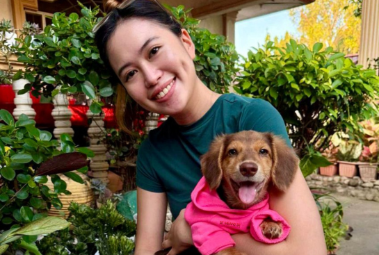 Alyssa Villanueva, office manager at Talking Tails Dog Training, holding a dachshund
