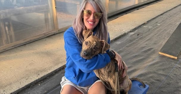 Susie Tramel, sales at Talking Tails Dog Training, holding a brindle rescue dog